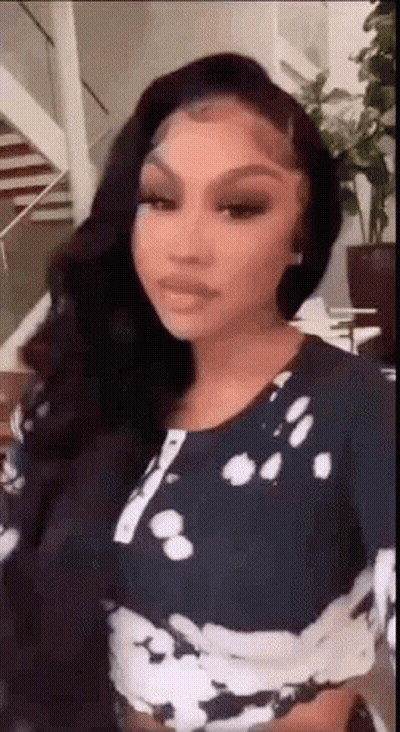A Woman With Long Black Hair Is Wearing A Tie Dye Crop Top And Standing In Front Of A Staircase . GIF