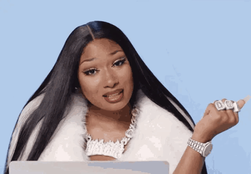 A Woman With Long Black Hair Is Wearing A White Fur Coat And Holding A Laptop . GIF