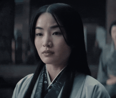 A Woman With Long Black Hair Is Wearing A White Jacket GIF