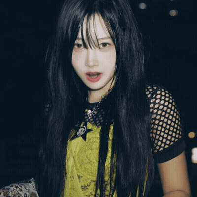 A Woman With Long Black Hair Is Wearing A Yellow Shirt With A Star On The Front GIF