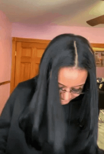 A Woman With Long Black Hair Is Wearing Glasses And Covering Her Face With Her Hair GIF