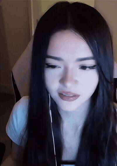 A Woman With Long Black Hair Is Wearing Headphones And Looking At The Camera GIF