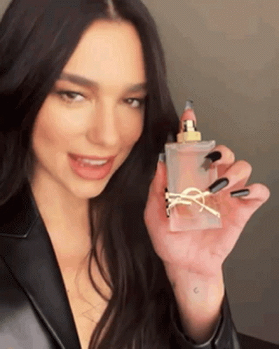 A Woman With Long Black Nails Is Holding A Bottle Of Perfume In Her Hand . GIF