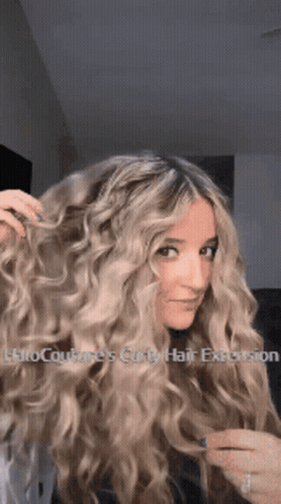 A Woman With Long Blonde Curly Hair Has A Halo Couture 'S Curly Hair Extension In Her Hair . GIF