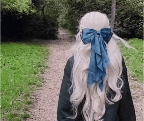 A Woman With Long Blonde Hair And A Blue Bow In Her Hair GIF