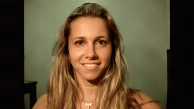 A Woman With Long Blonde Hair And A Dragonfly Necklace Is Smiling . GIF