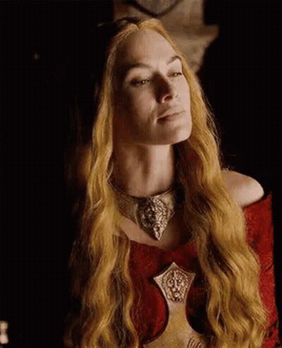 A Woman With Long Blonde Hair And A Necklace Is Wearing A Red Dress . GIF