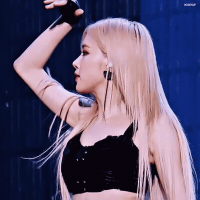 A Woman With Long Blonde Hair And A Tattoo On Her Arm Is Wearing A Black Top And Earrings . GIF