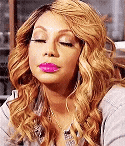 A Woman With Long Blonde Hair And Pink Lipstick Is Making A Funny Face With Her Eyes Closed . GIF