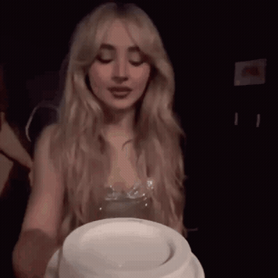 A Woman With Long Blonde Hair Is Holding A White Plate In Front Of Her Face . GIF