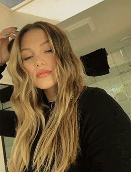 A Woman With Long Blonde Hair Is Looking At The Camera GIF