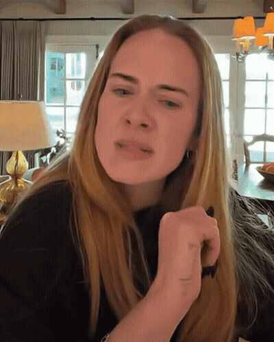 A Woman With Long Blonde Hair Is Making A Funny Face In A Living Room GIF