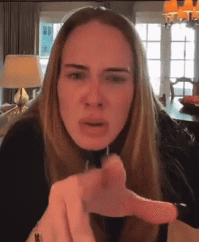 A Woman With Long Blonde Hair Is Pointing At The Camera . GIF