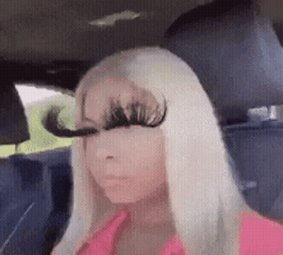 A Woman With Long Blonde Hair Is Sitting In A Car With Her Eyes Closed . GIF