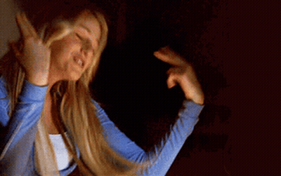 A Woman With Long Blonde Hair Is Smiling And Making A Peace Sign GIF