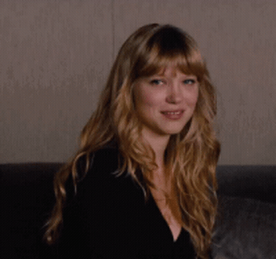 A Woman With Long Blonde Hair Is Smiling While Wearing A Black Top GIF