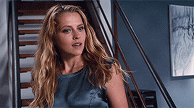 A Woman With Long Blonde Hair Is Standing On A Set Of Stairs Looking At The Camera GIF