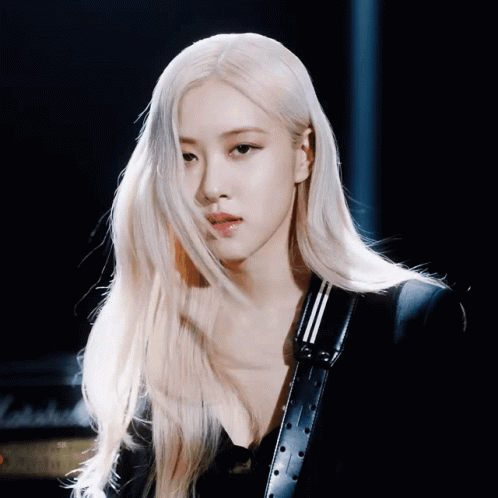 A Woman With Long Blonde Hair Is Wearing A Black Jacket And A Black Belt GIF