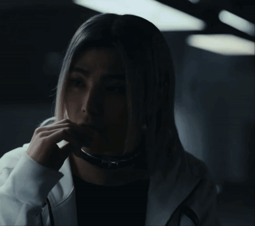 A Woman With Long Blonde Hair Is Wearing A Black Shirt And A White Hoodie GIF