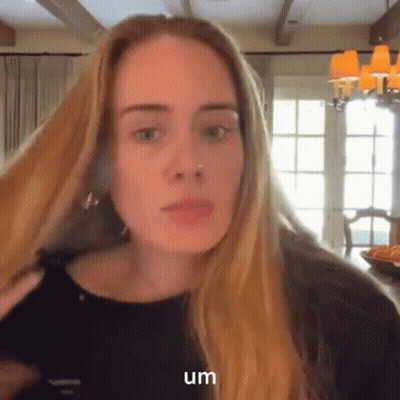 A Woman With Long Blonde Hair Is Wearing A Black Shirt And Earrings . GIF