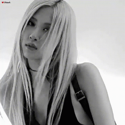 A Woman With Long Blonde Hair Is Wearing A Black Tank Top And A Choker GIF