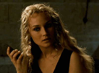 A Woman With Long Blonde Hair Is Wearing A Black Top And Earrings GIF