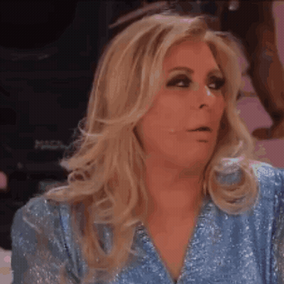 A Woman With Long Blonde Hair Is Wearing A Blue Shirt And Making A Funny Face . GIF