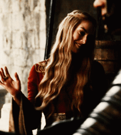 A Woman With Long Blonde Hair Is Wearing A Red Top And A Belt With The Letter S On It GIF