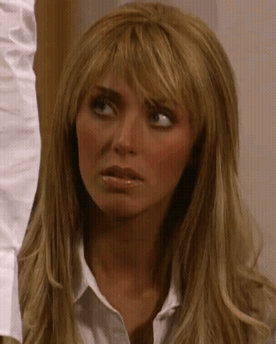 A Woman With Long Blonde Hair Is Wearing A White Shirt And Making A Funny Face GIF