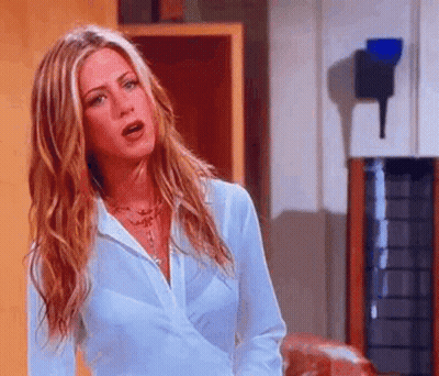 A Woman With Long Blonde Hair Is Wearing A White Shirt And Necklace . GIF