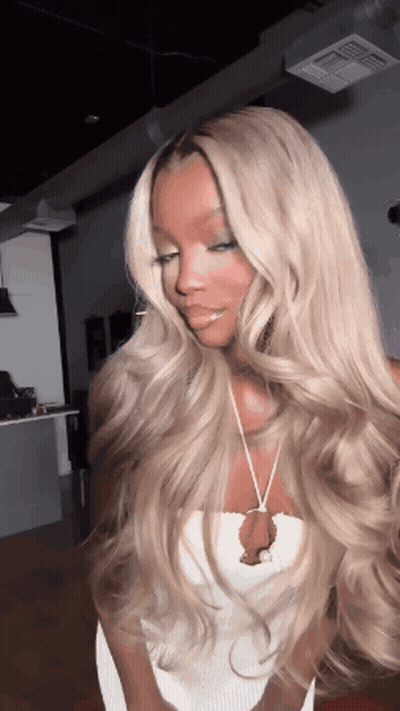 a woman with long blonde hair is wearing a white top and a necklace .