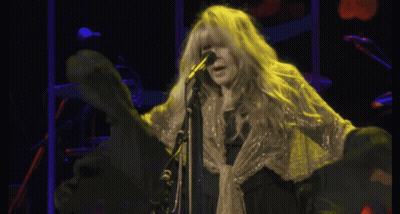 A Woman With Long Blonde Hair Singing Into A Microphone On A Stage GIF