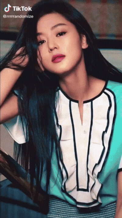 A Woman With Long Blue Hair Is Wearing A Blue And White Shirt With The Letter V On It GIF