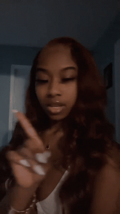 A Woman With Long Brown Hair And White Nails Is Standing In A Room . GIF