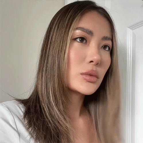 A Woman With Long Brown Hair Is Looking At The Camera GIF