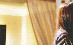 A Woman With Long Brown Hair Is Standing In Front Of A Curtain . GIF