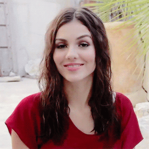 A Woman With Long Brown Hair Wearing A Red Shirt Smiles For The Camera GIF