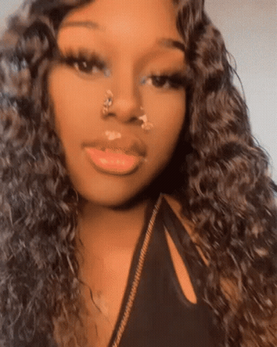 A Woman With Long Curly Hair And A Nose Ring Is Taking A Selfie . GIF