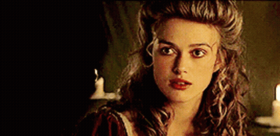 A Woman With Long Curly Hair And Red Lips Is Standing In Front Of A Candle . GIF