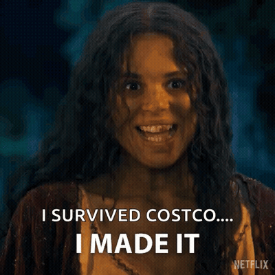 A Woman With Long Curly Hair Is Smiling And Saying `` I Survived Costco ... I Made It '' . GIF