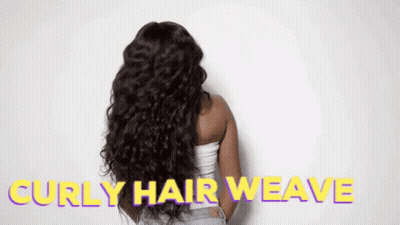 A Woman With Long Curly Hair Is Standing In Front Of A White Wall With The Words `` Curly Hair Weave '' Written On It . GIF