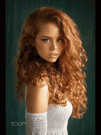 A Woman With Long Curly Red Hair And Freckles Is Wearing A White Dress GIF