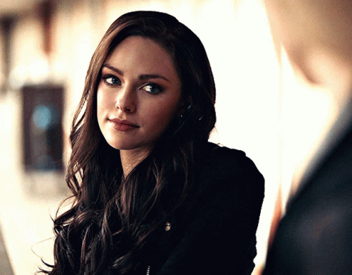 A Woman With Long Dark Hair Is Looking At A Man GIF