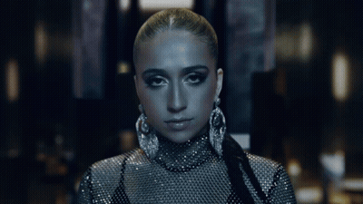 A Woman With Long Dark Hair Is Looking At Herself In A Mirror GIF