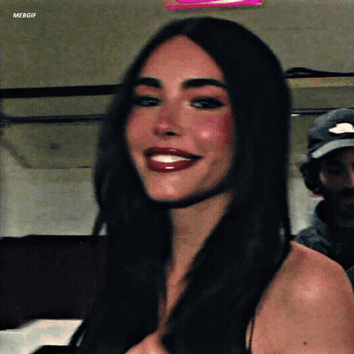 A Woman With Long Dark Hair Is Smiling For The Camera While Wearing Red Lipstick . GIF