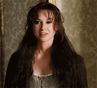 A Woman With Long Dark Hair Is Standing In Front Of A Wall . GIF