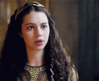 A Woman With Long Dark Hair Is Wearing A Headband And A Crown . GIF