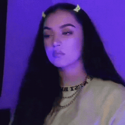 A Woman With Long Dark Hair Is Wearing A Necklace And A Hair Clip . GIF