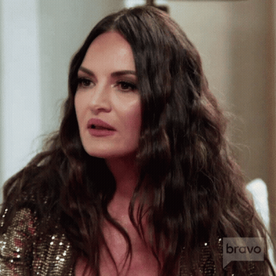 A Woman With Long Dark Hair Is Wearing A Sequined Top With Bravo Written On The Bottom GIF
