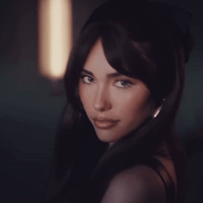 A Woman With Long Dark Hair Looks At The Camera GIF